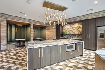 a large kitchen with marble countertops and a chandelier at Link Apartments® Broad Ave, Memphis, Tennessee